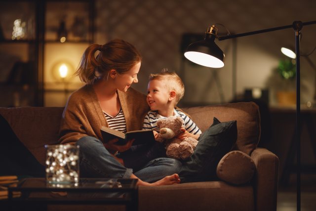Mom and son reading a book under a light.