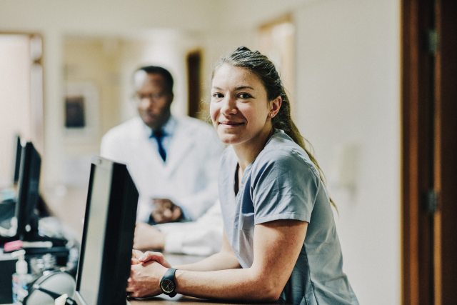Nurse at computer with doctor in background