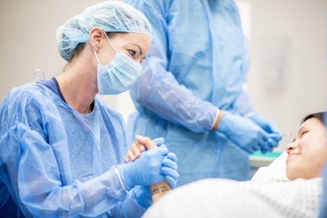 Nurse holds hand of surgery patient