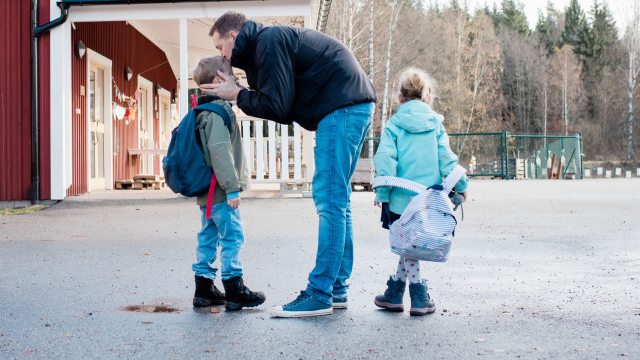 A dad says good-bye to young children at school