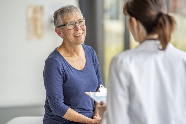 Older woman smiles as she talks with woman doctor
