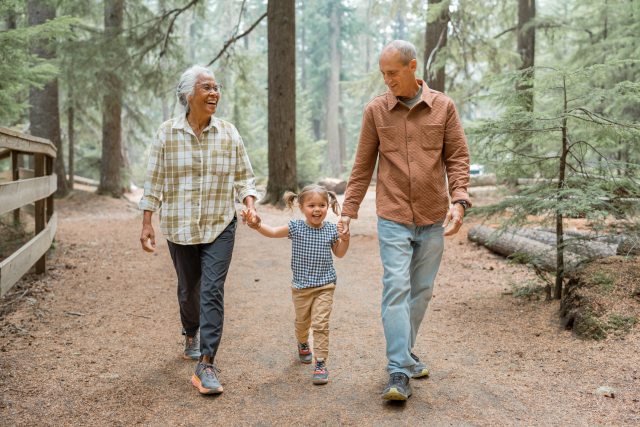 Grandmother, young child and grandfather walking on a wooded trail in the Pacific Northwest USA