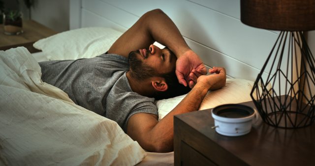 Man with a beard lying awake in bed