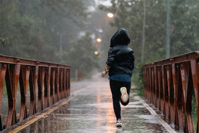 Woman running on a bridge in the rain.