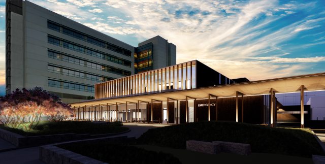 PeaceHealth Southwest Medical Center's new Emergency Department at sunset. The two-story building is illuminated with lights and the sky is blue, streaked with white clouds.