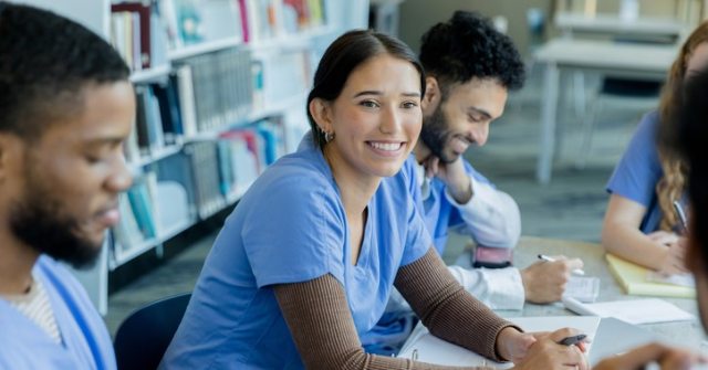 A nurse sitting at a desk looking at a teacher or something else offscreen