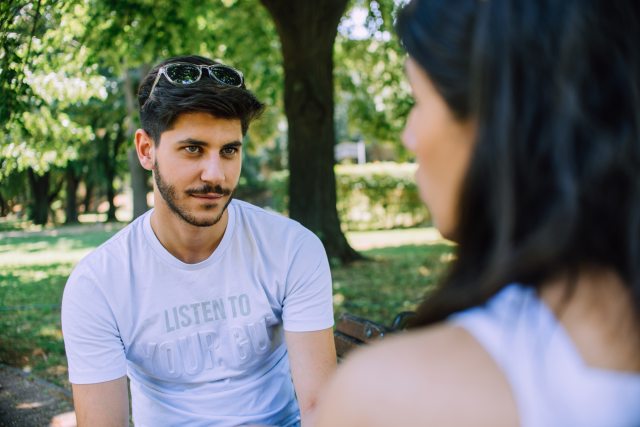 Young man and woman talking in a park setting