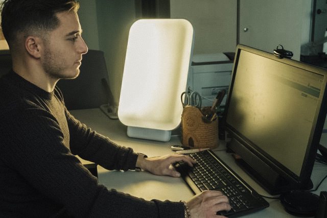 Man working at computer with happiness light next to him.