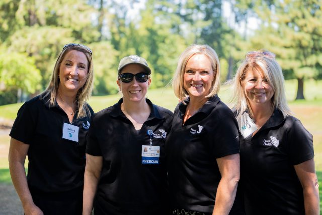 4 women in black peacehealth shirts smiling at the camera