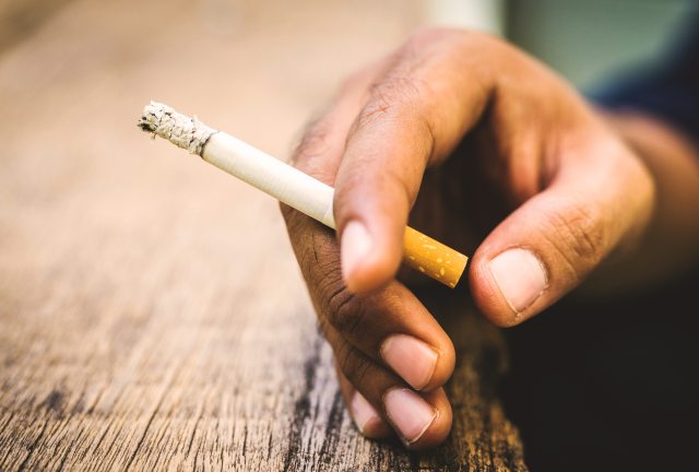 Close-up of a hand holding a lit cigarette