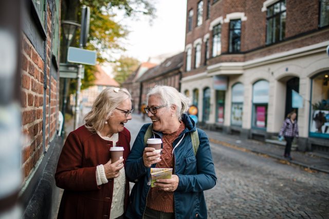 Two people joyfully talk while walking outside 