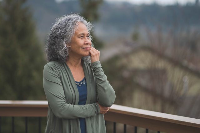 Woman looks thoughtful while standing outside on an overcast day