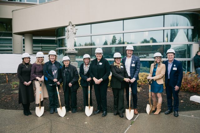 A group of people holding shovels and wearing hard hats ready to "break ground" on the peter paulsen pavilion
