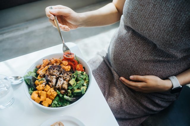 Close-up of bowl of healthy food in front of pregnant person