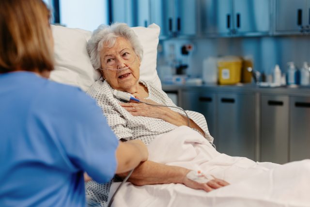 Nurse talks to a woman in a hospital bed