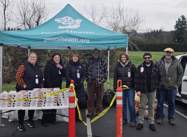 Peacehealth caregivers under peacehealth tent providing thanksgiving baskets