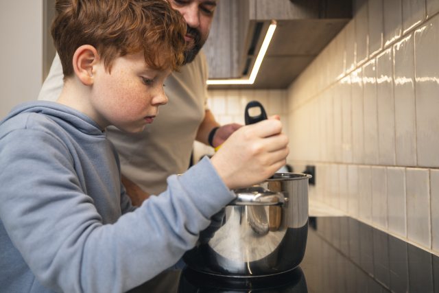Boy and dad stir a pot of soup