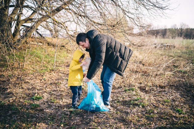Dad and young child pick up litter outdoors during the winter