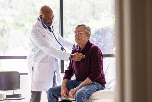 Doctor uses a stethoscope to listen to a man's heart