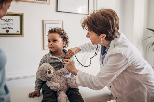 A pediatrician uses a stethoscope to examine a small child 