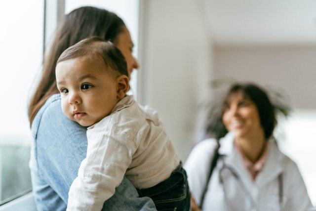 A mother holds her baby while speaking with a clinician