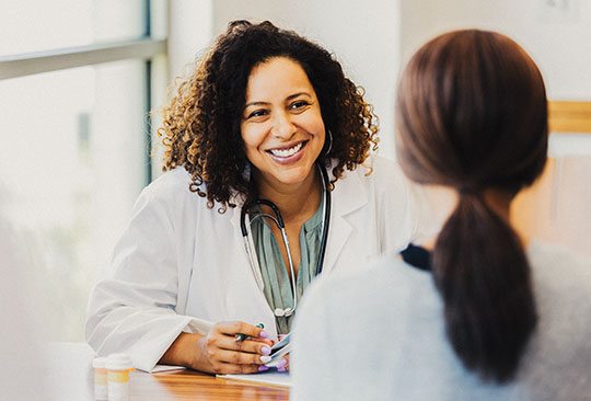 A smiling clinician speaks to a patient