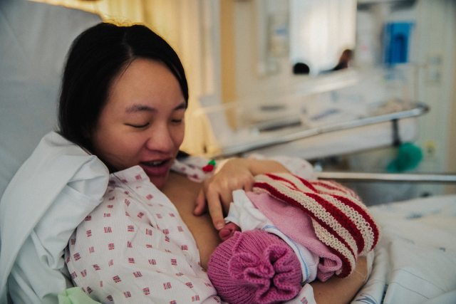 Mom nursing newborn baby in hospital bed