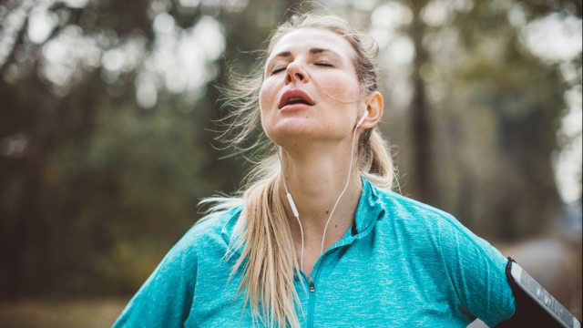 Exhausted runner with eyes closed, face tilted up