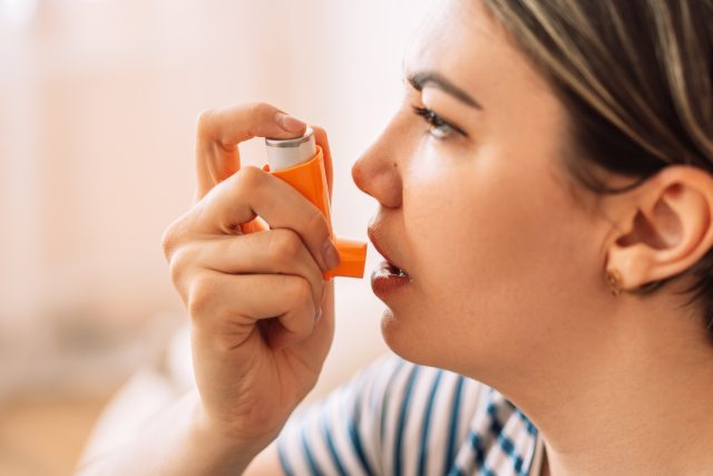 Woman holds inhaler up to her mouth