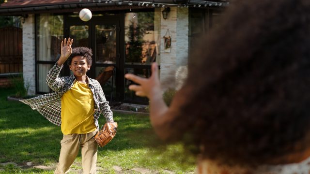 Boy and girl play catch with a baseball in yard