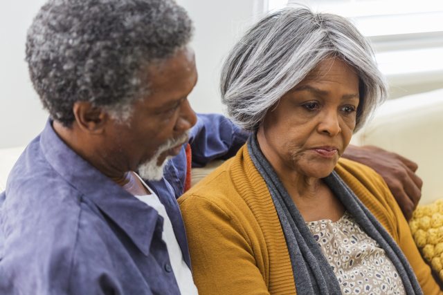 Man puts arm around the shoulder of a sad woman