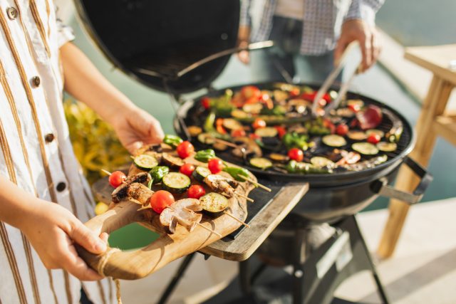 Hands of woman holding tray of veggie kabobs for grilling