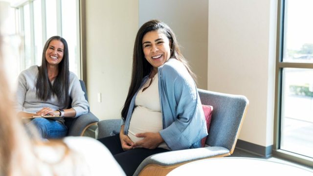 A pregnant woman smiles while sitting in a PeaceHealth OB/GYN clinic in Whatcom County 