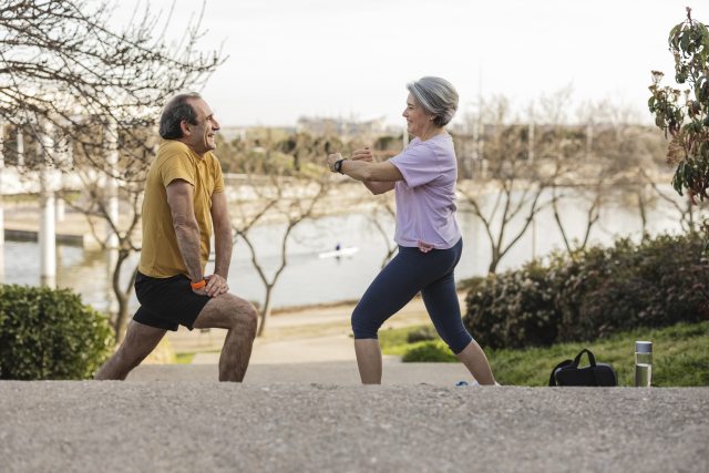 man and woman in workout clothes do stretching exercises while outside