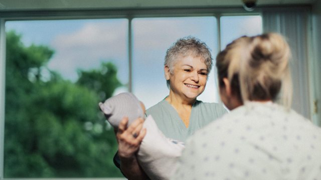 A PeaceHealth caregiver in the background smiles and speaks with a patient in the foreground