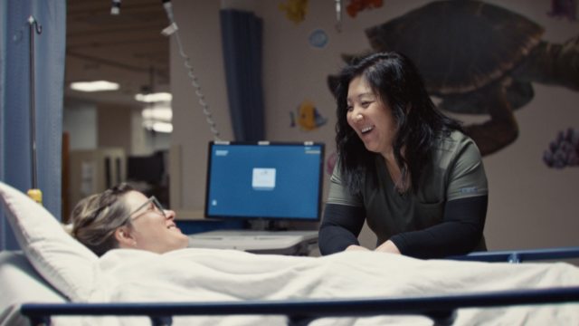 A caregiver sits bedside with a young patient.