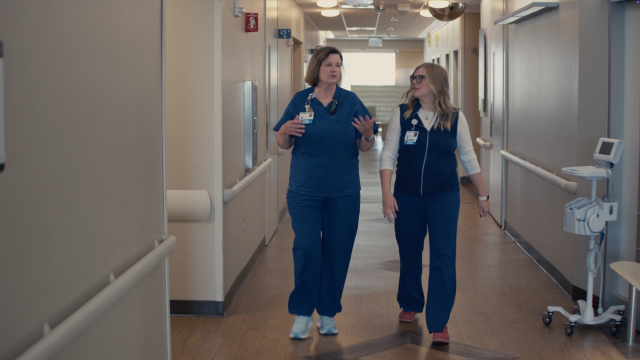 Two caregivers walk down a medical center hallway