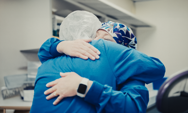 Two nurse caregivers embrace
