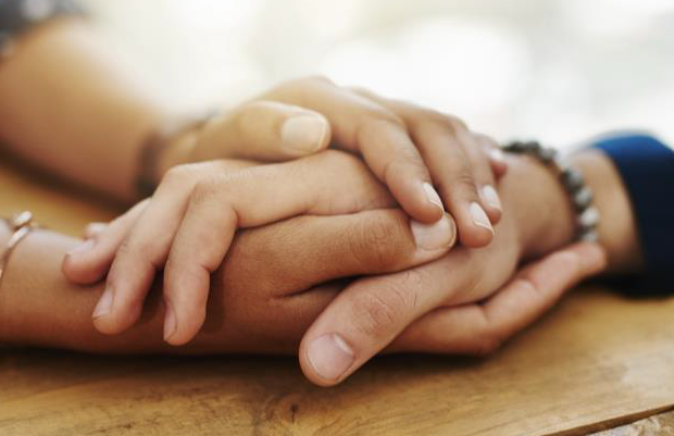 Close up of hands clasped in support