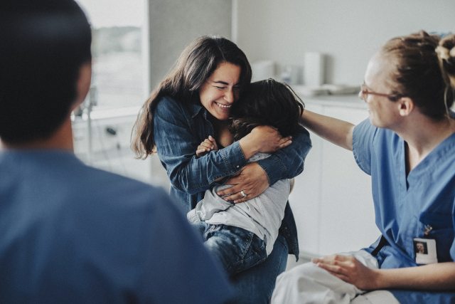 A mother embraces her child in a clinical setting