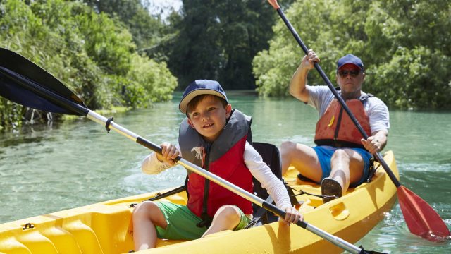 Child and man paddle in a yellow canoe