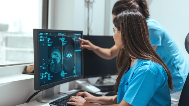 Two nurses view a scan on a computer monitor