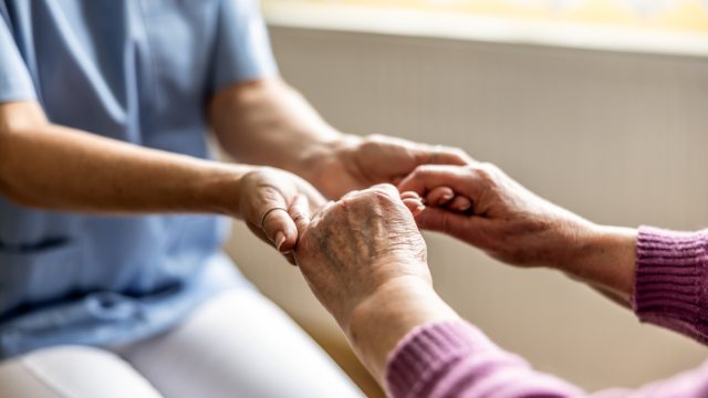 A caregiver and patient grasp hands