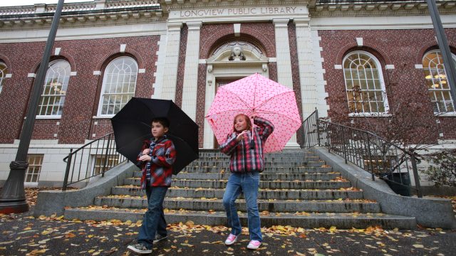 Two children with umbrellas walking down the steps of the public library