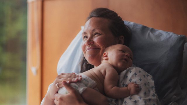 A happy mother holds her newborn child