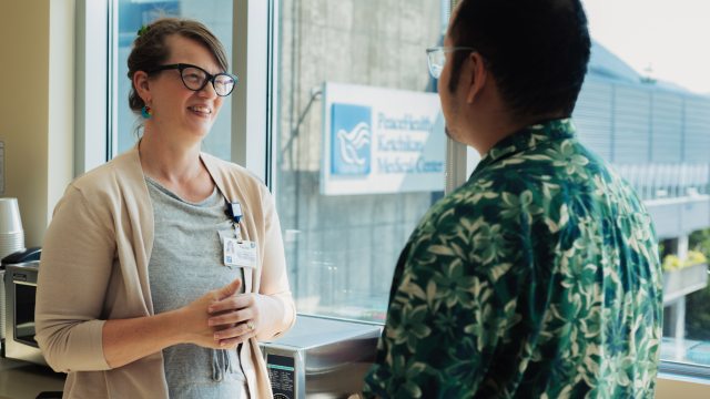 A PeaceHealth caregiver speaks with a patient in a clinical setting