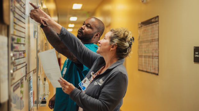 Two PeaceHealth caregivers discuss a patient triage board