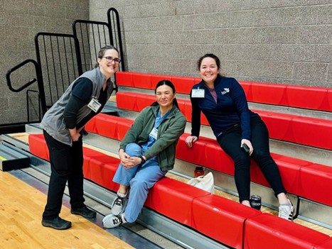 Amanda Stout, RN; Mal Takenaga, RN, and Leslie Clark pose on high school gymnasium bleachers