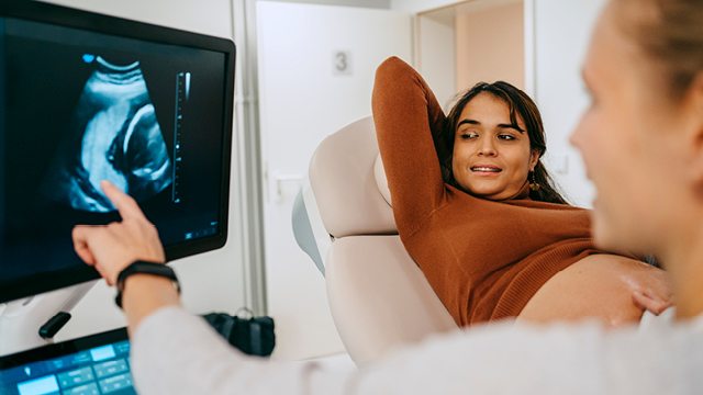 A caregiver speaks with an expectant mother about an ultrsound image 