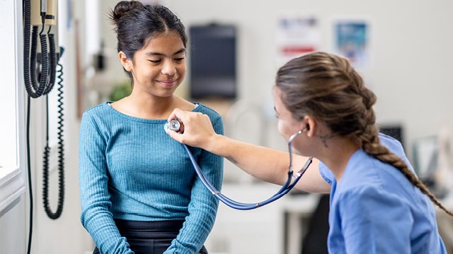 A caregiver uses a stethoscope to examinethe lungs and heart of a young patient